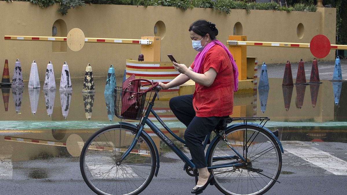 امرأة تضع على وجهها قناعا للحد من انتشار مرض كوفيد-19 بعد هطول أمطار غزيرة في بيكين - 2020/06/25