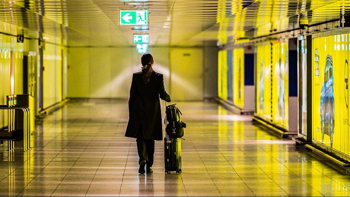  Una donna cammina con la sua valigia lungo un corridoio vuoto dell'aeroporto del Reno-Meno. 12 marzo 2020 