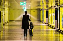  Una donna cammina con la sua valigia lungo un corridoio vuoto dell'aeroporto del Reno-Meno. 12 marzo 2020