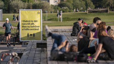 People enjoy the warm evening weather in Malmo, Sweden, Tuesday May 26, 2020 as a sign reads 'In Malmo everything is near. But now we need to keep a distance'. 