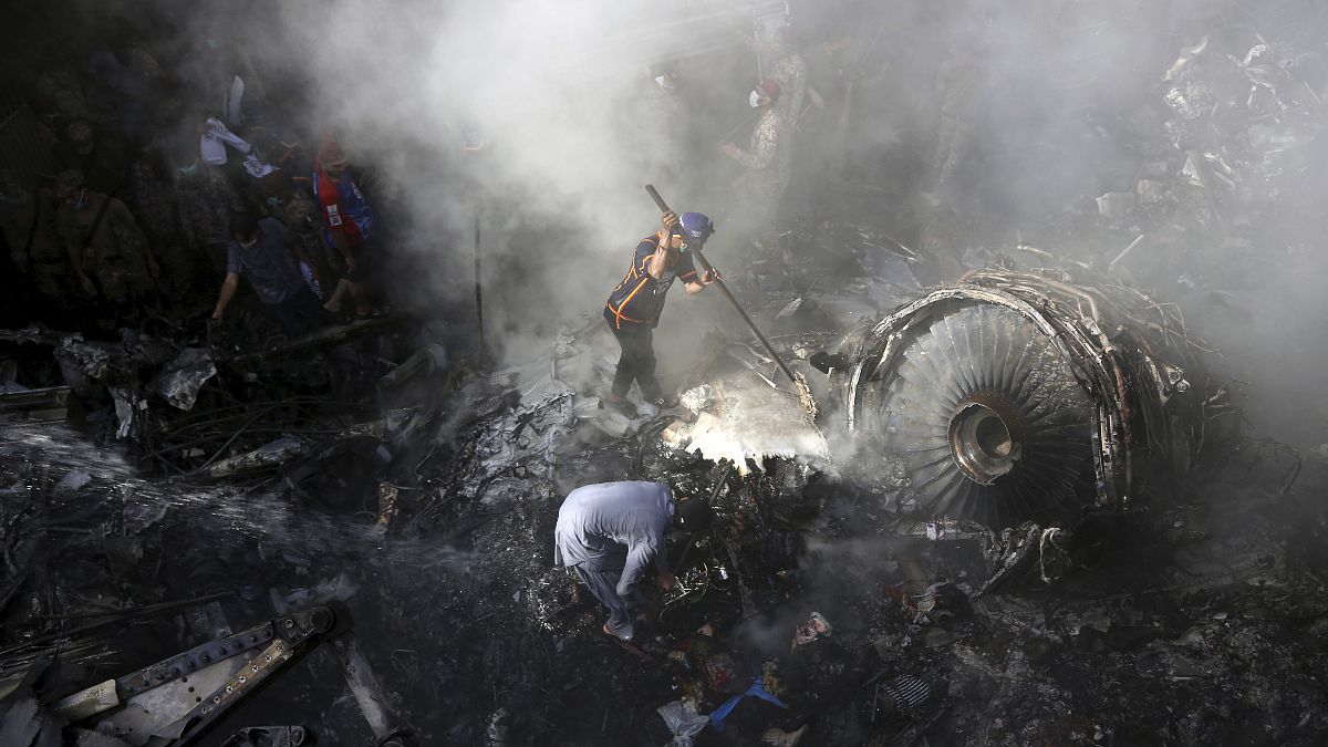 In this May 22, 2020 file photo, volunteers look for survivors of a Pakistan International Airlines plane that crashed in a residential area of Karachi, Pakistan.