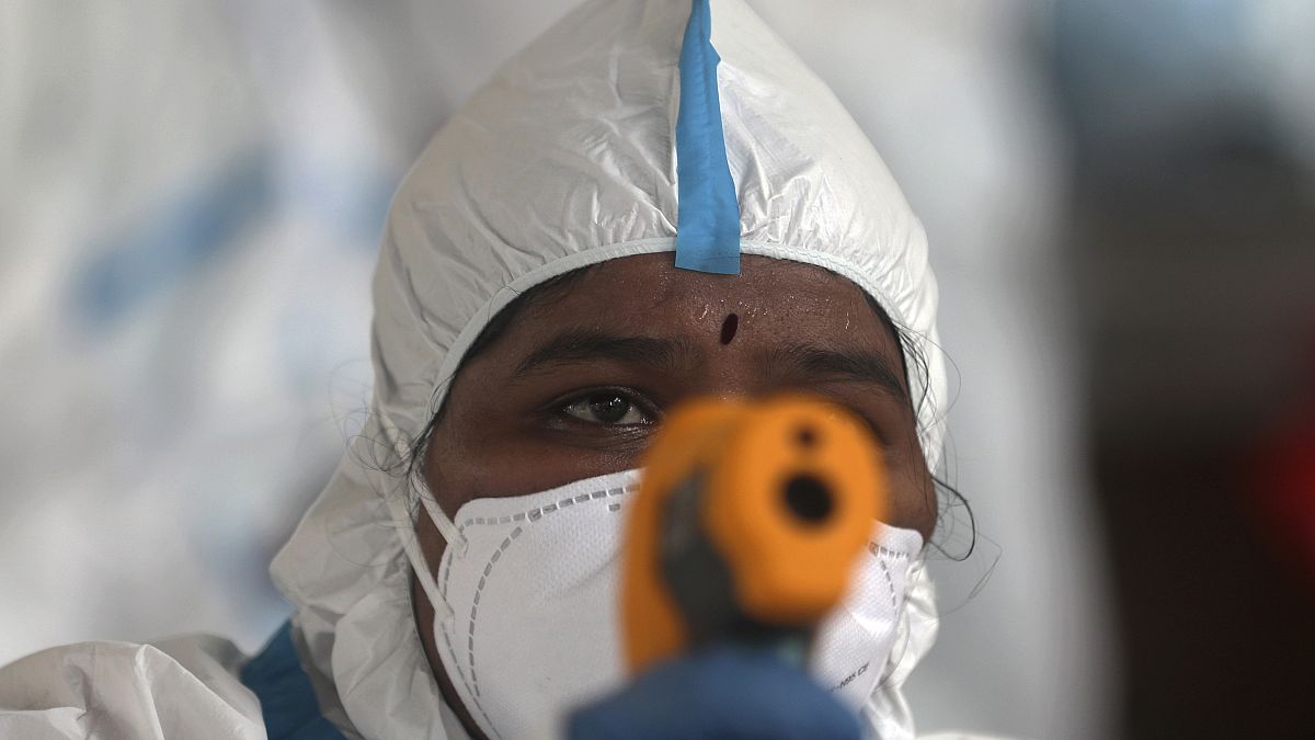 ممرض يقيس درجة حرارة امرأة في مخيم في "درافي" في مومباي في الهند - 2020/06/26