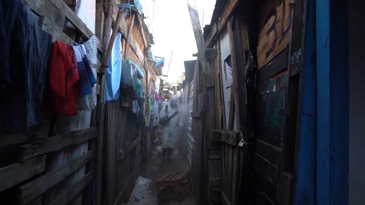 Volunteers spreading disinfectant in alleyways of squat 