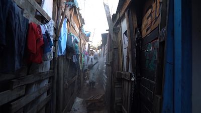 Volunteers spreading disinfectant in alleyways of squat