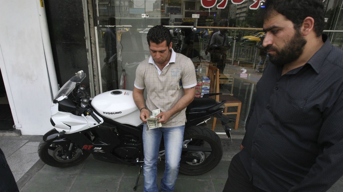 A street money exchanger, center, counts US dollars, in downtown Tehran, Iran