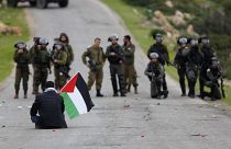 Filistin bayrağı ile ABD Başkanı Donald Trump'ın 'Ortadoğu Barış Planı'na karşı çıkan bir Filistinli eylemci ve İsrail askerleri / Ürdün Vadisi
