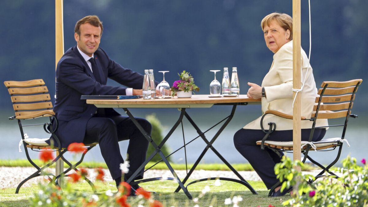 German Chancellor Angela Merkel and French President Emmanuel Macron, left, talk during a bilateral meeting at the German government's guest house Meseberg Castle near Berlin