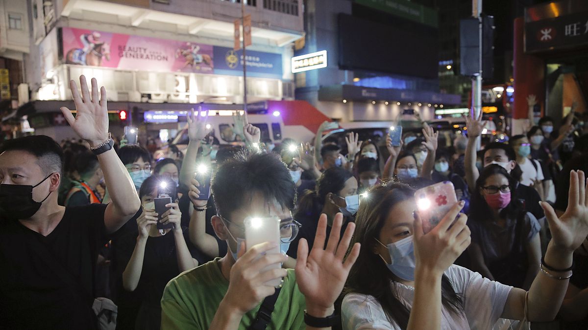 Protesters gesture with five fingers, signifying the "Five demands - not one less" during a protest in Mong Kok, Hong Kong, Friday, June 12, 2020. 