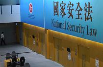 A government staff walks past a big banner featuring the Hong Kong National Security Law at the government headquarters in Hong Kong, Tuesday, June 30, 2020.