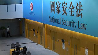 A government staff walks past a big banner featuring the Hong Kong National Security Law at the government headquarters in Hong Kong, Tuesday, June 30, 2020.