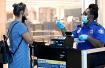 L'agent de la TSA Patrisa Johnson, à droite, aide un voyageur à passer la sécurité avant de s'envoler de Love Field à Dallas, le mercredi 24 juin 2020.