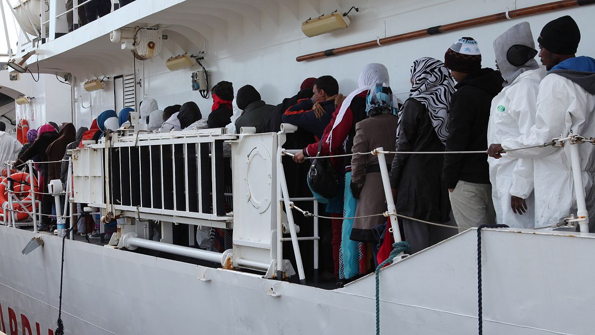 مهاجرون ينتظرون النزول من الساحل الإيطالي