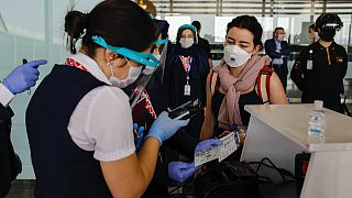 Sabiha Gökçen Havalimanı'ndan Londra'ya gitmek üzere olan uçağın yolcularına maskeli bir görevli bilet kontrolü yapıyor
