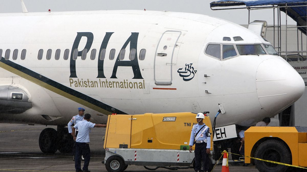 A Pakistan International Airlines passenger jet is parked on the tarmac at a military base in Makassar, Indonesia.