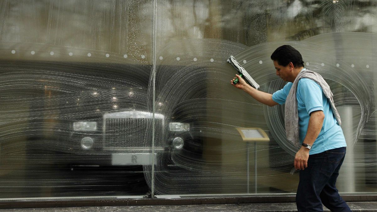 A window cleaner works on a window at a Rolls-Royce showroom in London