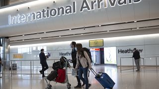 Passengers wearing face masks arrive at London's Heathrow Airport on June 8, 2020.