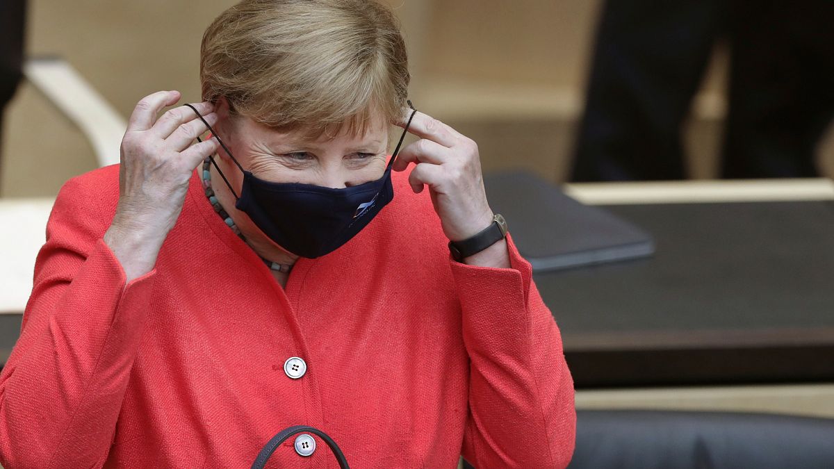 German Chancellor Angela Merkel adjusts her face mask