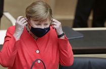 German Chancellor Angela Merkel adjusts her face mask