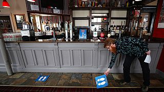 Owner Are Kjetil Kolltveit from Norway places markers for social distancing on the front of the bar at the Chandos Arms pub in London, Wednesday, July 1, 2020.