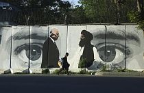 Az amerikai Zalmay Khalilzad és Mullah Abdul Ghani Baradar tálib tárgyaló képe egy kabuli falon