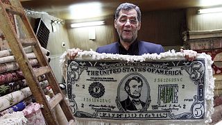Iranian shopkeeper holds a carpet in a US five dollar note design in the main Bazzar in Tabriz