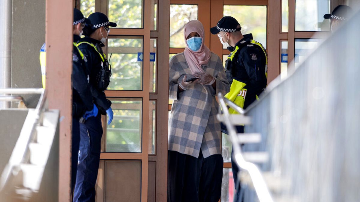 Polícia fala com uma residente de um complexo de apartamentos em confinamento em Melbourne