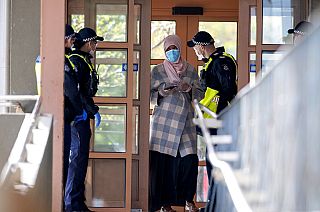 Polícia fala com uma residente de um complexo de apartamentos em confinamento em Melbourne