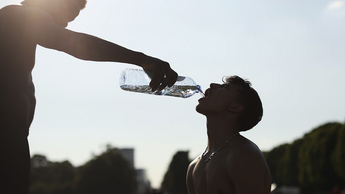 Un entrenador da agua a su estudiante durante una sesión de entrenamiento en un caluroso día de verano en Bruselas el 25 de junio de 2020. 