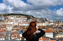 A woman takes pictures from the top of Lisbon