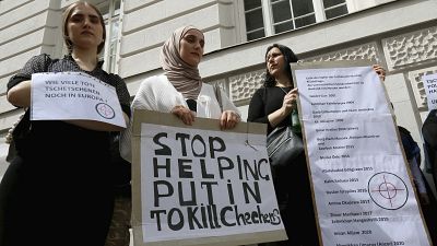 Chechen protesters hold a banner that reads "Stop helping Putin to kill Chechens" outside of the Russian embassy in Vienna on Tuesday