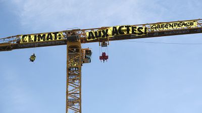Greenpeace activists scale a crane at Notre Dame cathedral in climate protest