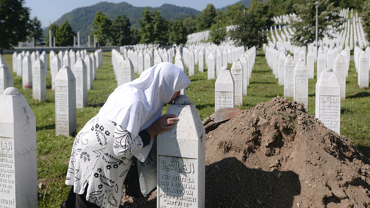 A woman kisses a grave stone in Potocari, near Srebrenica, Bosnia, Saturday, July 11, 2020. Nine newly found and identified victims of the 1995 genocide were laid to rest.
