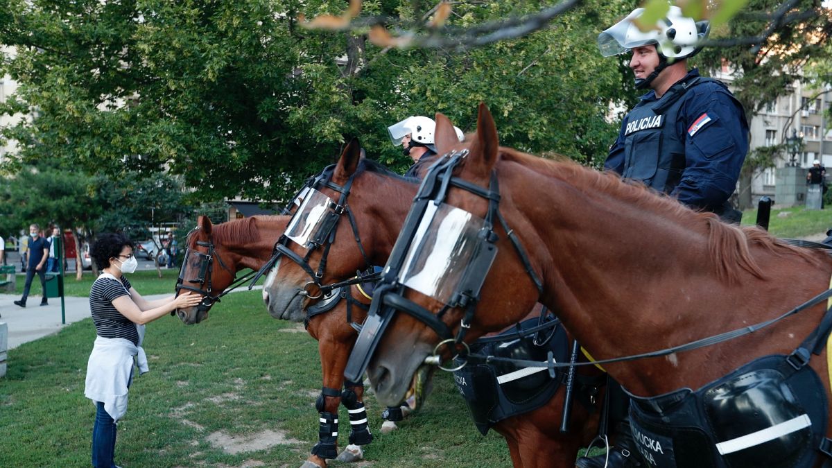 A rohamrendőrség lovát kényezteti egy járókelő Belgrádban