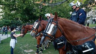 A rohamrendőrség lovát kényezteti egy járókelő Belgrádban