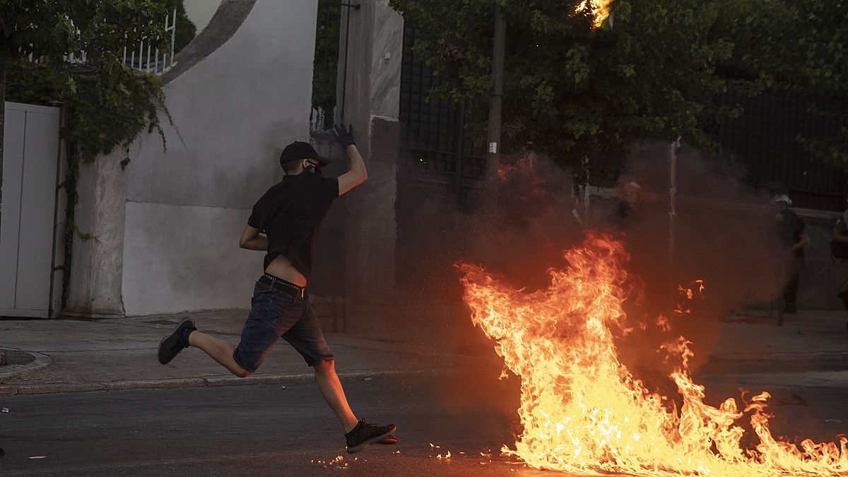 A protester throws a petrol bomb at riot police outside the Greek Parliament during a demonstration against new protest law in Athens, on Thursday July 9, 2020. 