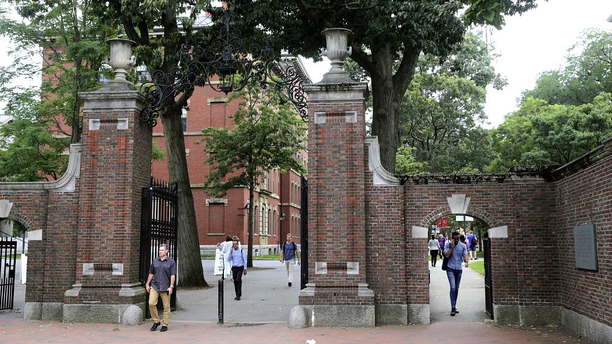 FILE - In this Aug. 13, 2019, file photo, pedestrians walk through the gates of Harvard Yard at Harvard University in Cambridge, Mass.