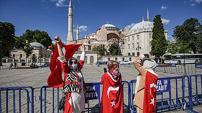 Ciudadanos envueltos en la bandera turca celebran la conversión de la basílica de Santa Sofía en mezquita