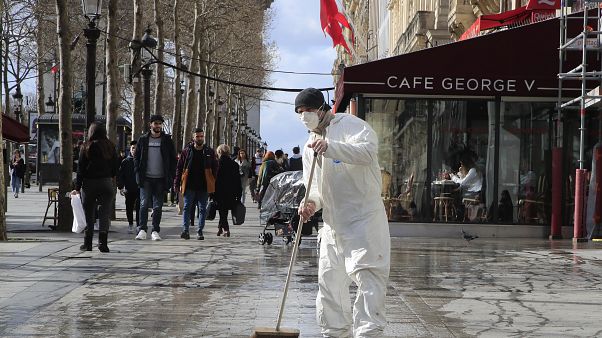 A masked worker wipes the pavement of the Champs Elysees avenue in Paris, Friday, March 13, 2020. A masked worker wipes the pavement of the Champs Elysees avenue in Paris, Friday, March 13, 2020.