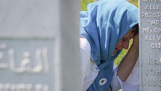 A mourner cries at the graveside of a loved one at 25th anniversary commemorations of Srebrenica.