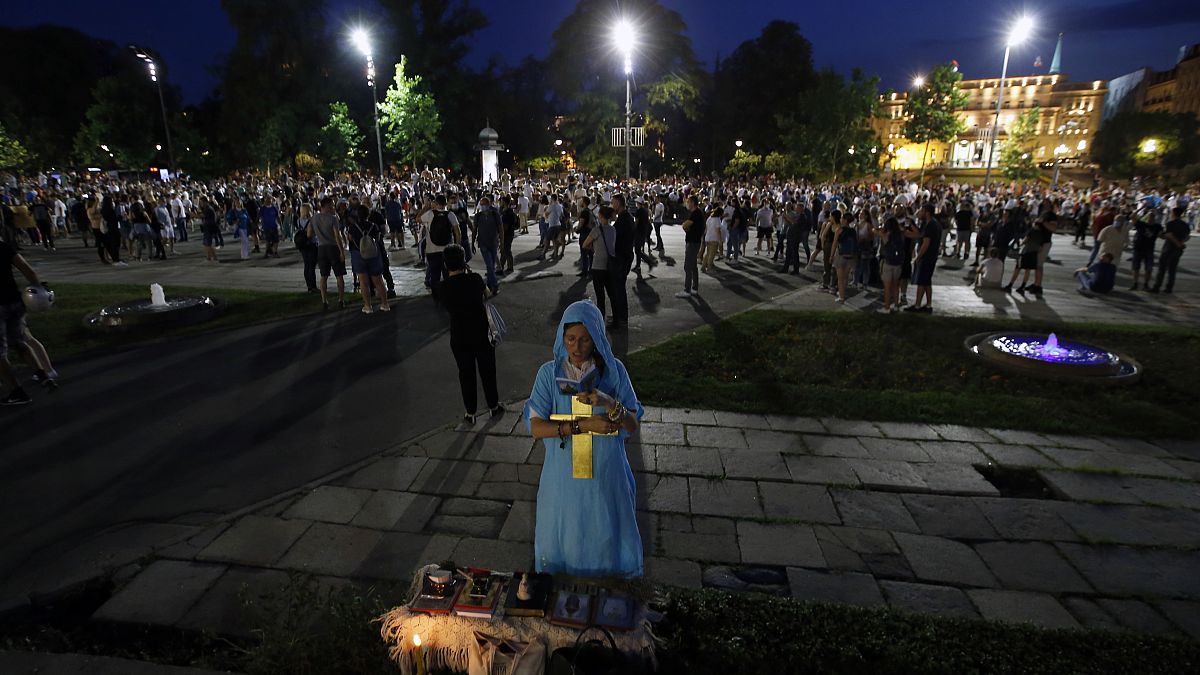 Uma mulher reza durante os protestos de sábado à noite em Belgrado