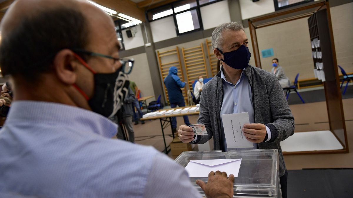 Inigo Urkullo, Basque Lehendakari or Regional President, right, wears a face mask while voting in Basque regional elections.