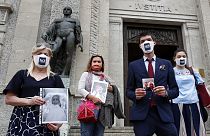 Members of Noi Denunceremo (We will denounce) Facebook group, holds pictures of their relatives, victims of COVID-19, as they stand in front of Bergamo's court.