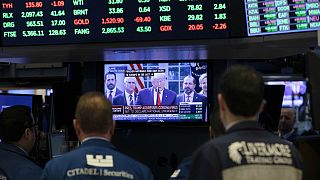 Traders listen at the New York Stock Exchange to President Donald Trump's televised speech from the White House