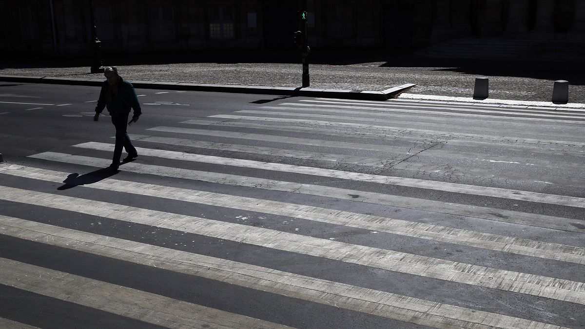 A man crosses an empty street during a nationwide confinement to counter the Covid-19, in Paris, Saturday, April 4, 2020.