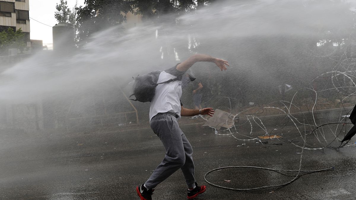 متظاهر لبناني يتعرض للرش بالمياه فيما كان يرمي الحجارة على الشرطة