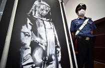 A policeman stands guard near a piece of art attributed to Banksy, that was stolen at the Bataclan in Paris in 2019