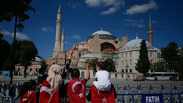 Török zászlóba burkolt emberek az átalakítás miatt bezárt isztambuli látványosság, az Hagia Sophia előtt Török zászlóba burkolt emberek az átalakítás miatt bezárt isztambuli látványosság, az Hagia Sophia előtt