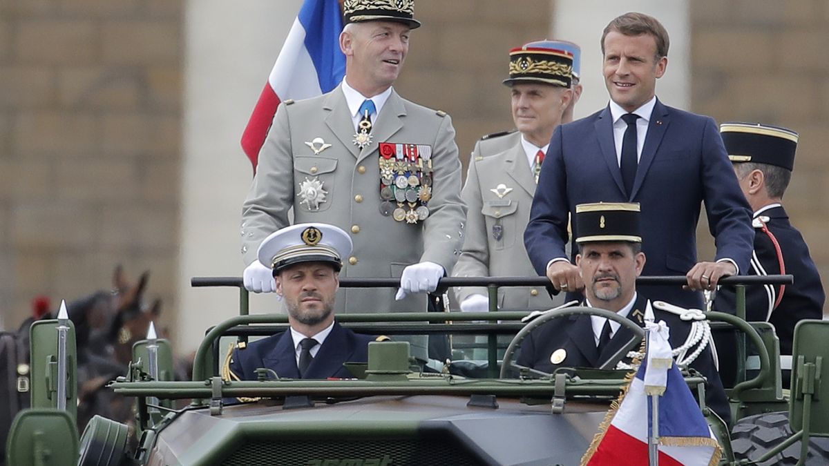 France's President Emmanuel Macron stands in the command car as he reviews troops before the start of the Bastille Day parade. 14 July, 2020.