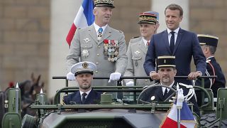 France's President Emmanuel Macron stands in the command car as he reviews troops before the start of the Bastille Day parade. 14 July, 2020.