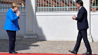 German Chancellor Angela Merkel, left, welcomes Italian Prime Minister Guiseppe Conte, right, for a meeting at the German government's guest house 'Meseberg' in Gransee